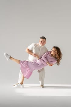 Beautiful young couple dancing on light background. Full length of young beautiful couple bonding while standing against white background