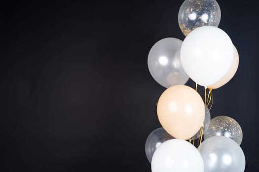 Bunch of balloons of white, beige and transparent colors on a dark background. Place for the inscription. High quality photo