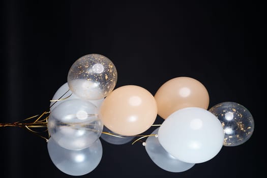 A bunch of balloons in white, beige and transparent colors on a dark background with space for an inscription. High quality photo