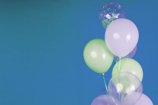 Balloons of light colors - white, light green, transparent on a blue background. High quality photo