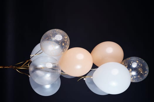 A bunch of balloons in white, beige and transparent colors on a dark background with space for an inscription. High quality photo