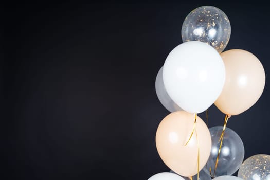 Bunch of balloons of white, beige and transparent colors on a dark background. Place for the inscription. High quality photo