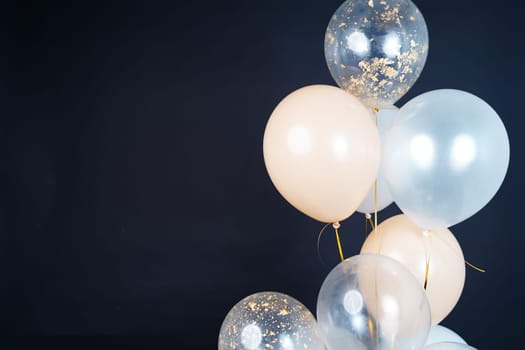 Bunch of balloons of white, beige and transparent colors on a dark background. Place for the inscription. High quality photo