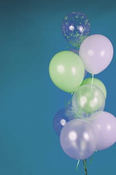 Balloons of light colors - white, light green, transparent on a blue background. High quality photo