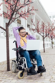 a man with disabilities near a building with a laptop and a phone