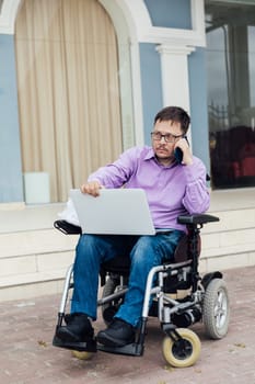 a man with disabilities near a building with a laptop and a phone