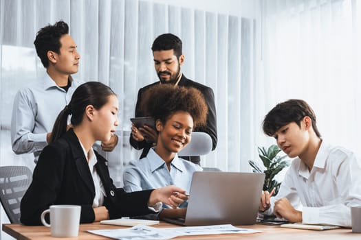 Happy diverse business people work together, discussing in corporate office. Professional and diversity teamwork discuss business plan on desk with laptop. Modern multicultural office worker. Concord