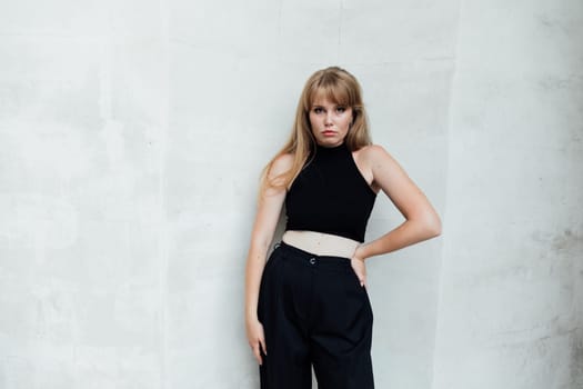 woman in black clothes stands against a white wall