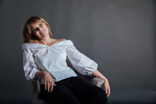 beautiful woman sitting in a chair on a gray background