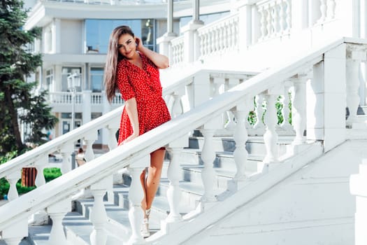 a woman in a red dress walk on the street rest trip stands on the stairs