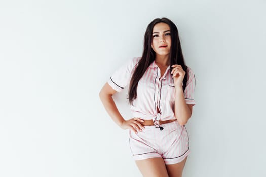 a brunette woman in pajamas on a white background in a bright room