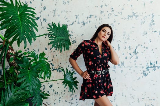 brunette woman posing near a green plant