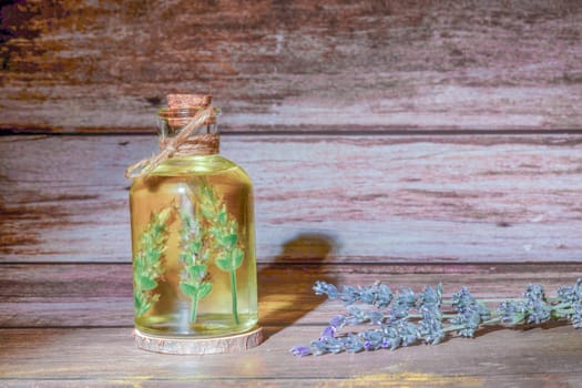 glass bottle with lavender oil with lavender branches inside on a wooden table