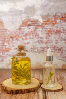 bottle of rosemary essential oil with fresh branches inside and dropper with oil ready for use on a wooden table