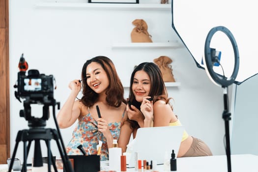 Asian Woman influencer shoot live streaming vlog video review makeup uttermost social media or blog. Happy young girl with cosmetics studio lighting for marketing recording session broadcasting online