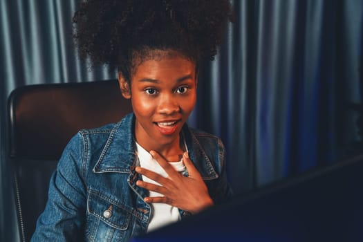 Young African American woman with surprise face, wearing blue jeans shirt and looking at final project document on laptop for planing next sequence. Concept of work at neat home place. Tastemaker.