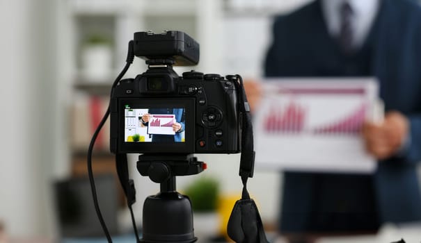 Male in suit and tie show stats graph pad making promo videoblog or photo session in office camcorder to tripod closeup. Vlogger selfie sale solution or finance advisor management information