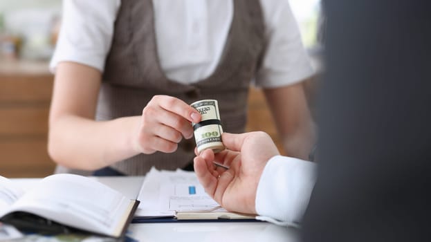 Businessman hands a cutlet out of money to a woman in the form of a bribe of salary in an envelope a dollar equivalent from hand to hand.