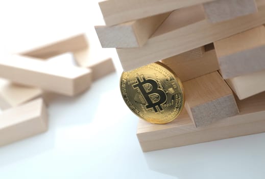 The bitcoin coin holds a game of wooden bricks embodying the basis of all the currency and exchange rate