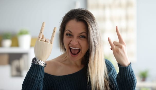 Portrait of crazy female screaming with joy and showing cool gesture with prosthetic and healthy arms. Cheerful blonde looking at camera with gladness. People with disabilities concept