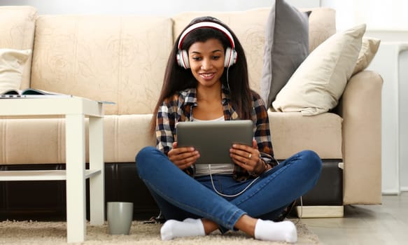 Black ordinary female american teen portrait at home sofa remote education concept. Girl hold tablet in hand music apps teacher checks homework online university library learning foreign languages