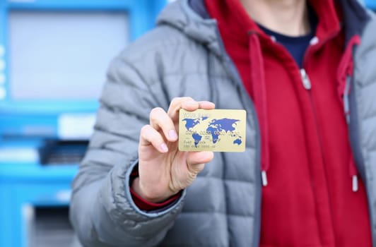 Male hand hold bank plastic card aganist atm background. Cash money payment system concept.