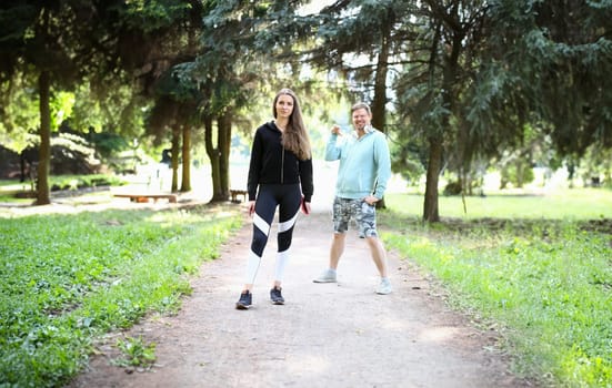 Portrait of beautiful bodybuilder and smiling man. Wonderful sportswoman wearing sportswear. Handsome boy with earphones having workout with trainer. Fitness and sport concept