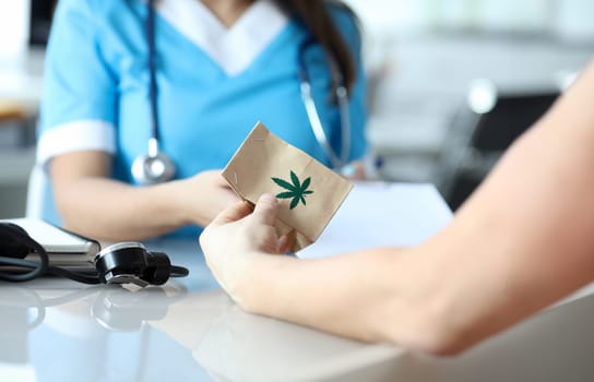 Female doctor writes prescription for medical marijuana to patient in hospital office. Legal marijuanna treatment concept