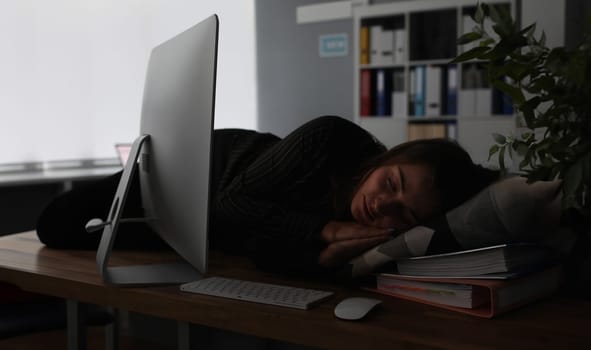 Businesswoman sleeping on office table evening time background. Woman wants to go home and lives at work. Overtime night work concept.