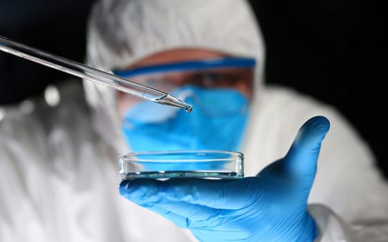 Male chemist look at test tube with yellow liquid biological research closeup. Conducts study urine materials content harmful substances microorganisms human heretical cloning concept