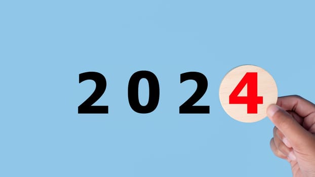 Stock trading. Finance. Investment. Growing business. Human hands are holding a wooden board with the letters 2024 representing the start of business growth in the year 2024.