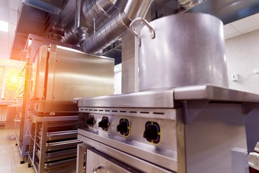 Industrial kitchen in school restaurant with professional equipment and pans