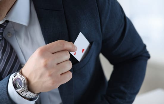 Closeup of mans hand pulling ace card out of suit pocket. Businessman in stylish outfit. Male with gambling addiction. Entertainment and casino concept