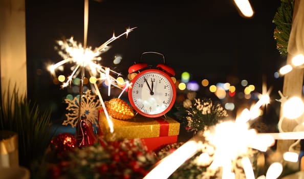 Red alarm clock with christmas gifts against night city background. Happy New Year concept