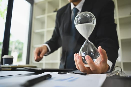 Hand of businessman holding hourglass. Business and time management concept.