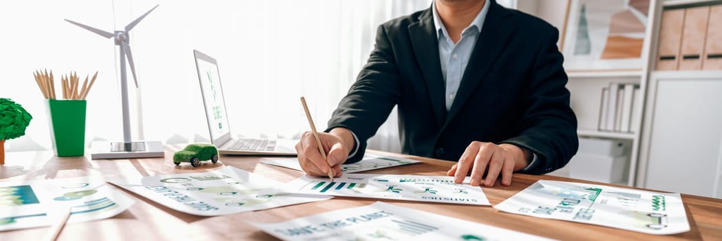 Businessman planning for green business strategy in office with paper documents focused on eco-friendly and energy sustainable policy to reduce CO2 emission for green environment. Trailblazing