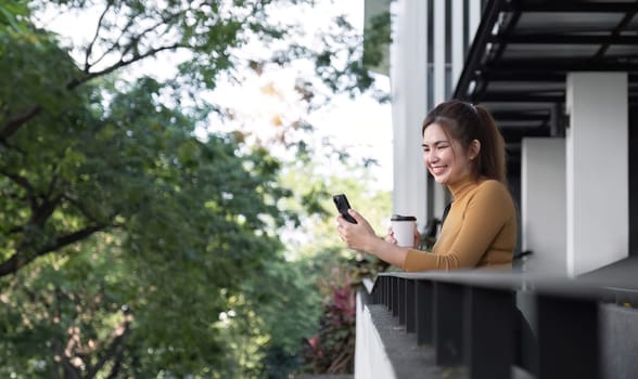 Successful Asian businesswoman standing and smiling Stay in the city using an application on your mobile phone. Read news on your smartphone fast connection Check out the outdoor mobile app.