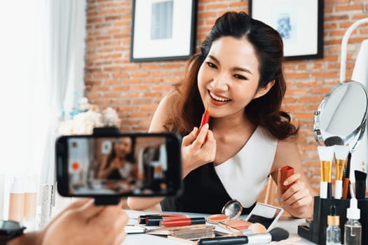 Asian Woman influencer shoot live streaming vlog video review makeup uttermost social media or blog. Happy young girl with cosmetics studio lighting for marketing recording session broadcasting online