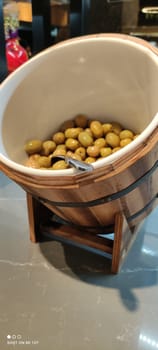 Olives close-up in the restaurant assortment in an original round-shaped container reminiscent of a barrel