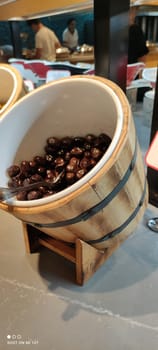 Olives close-up in the restaurant assortment in an original round-shaped container reminiscent of a barrel