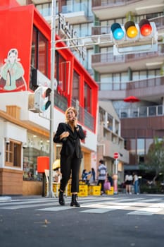 Asian professional businesswoman holding cellphone using smartphone standing or walking on big city urban street outside. Successful Asian business woman.