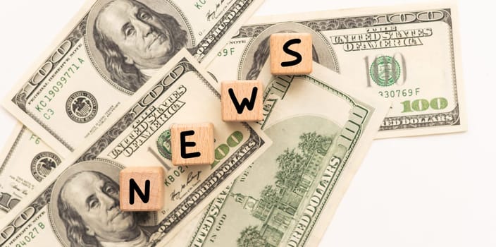 Concept words NEWS on wooden blocks on a beautiful background from dollar bills. Business. High quality photo