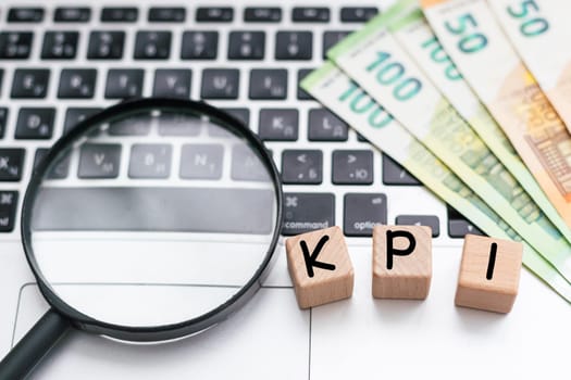 KPI written on wooden cube on keyboard with office tools. High quality photo
