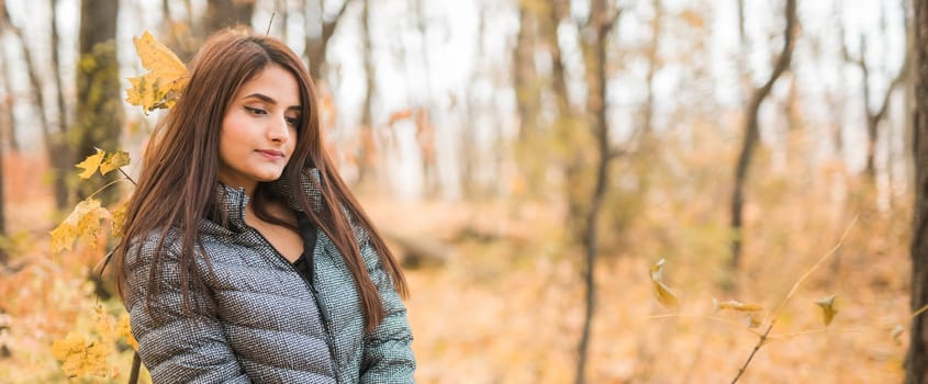 Close-up portrait of a young beautiful confident Indian Asian woman in fall outdoor. Happy and natural smiling female. Generation z and gen z youth