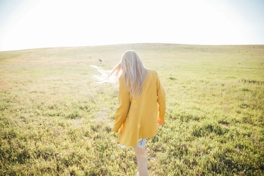blonde woman walking in nature on green grass in field walking journey