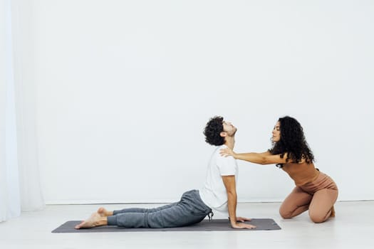 woman helps a man do gymnastics warm-up exercises yoga