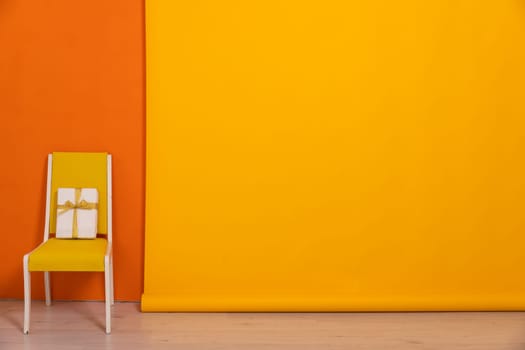 a yellow chair with gift on orange background in the room interior furniture