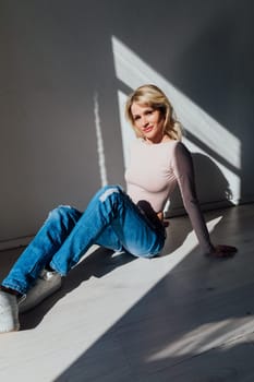 a blonde woman in jeans in sunset light in the room
