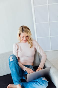 woman with a laptop in the room works remotely online internet communication