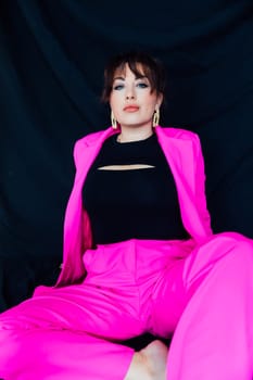 fashion woman brunette in bright clothes sits on black background